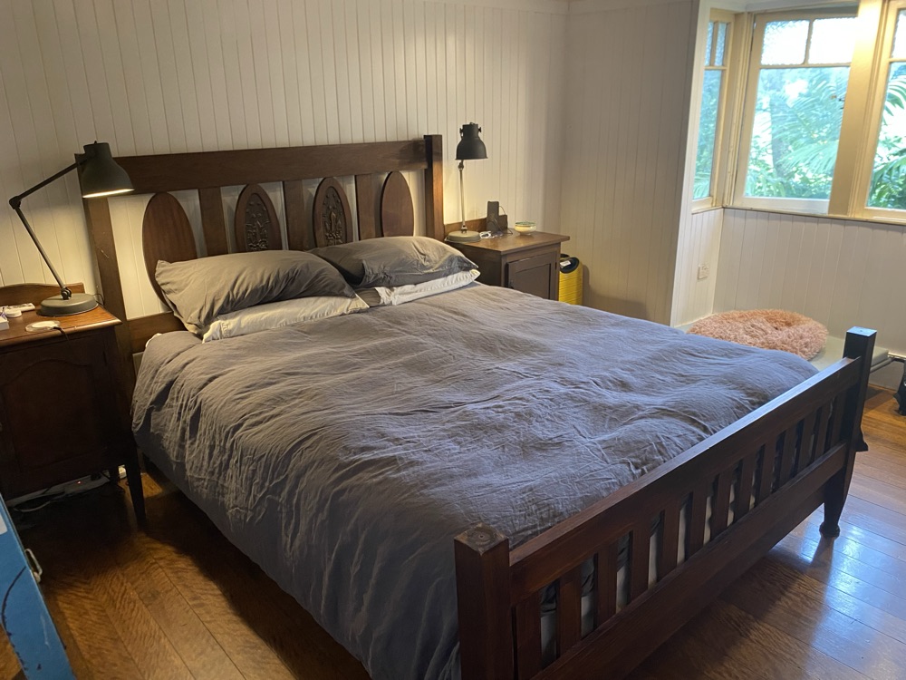 Queen bedroom with linen bedding and leafy outlook